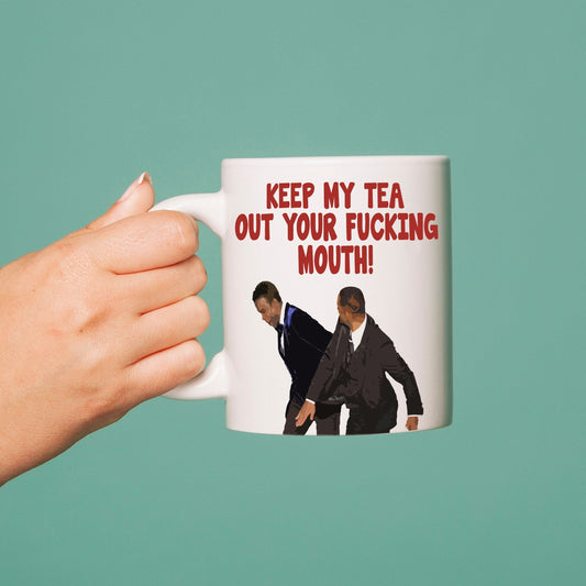 A white mug with a sublimation printed graphic featuring an image of two people and the text 'KEEP MY F*CKING tea out your mouth!'.