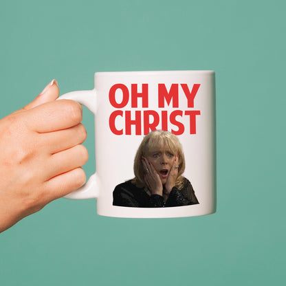 Mug with 'OH MY CHRIST' text and a person's face, held by a hand against a teal background