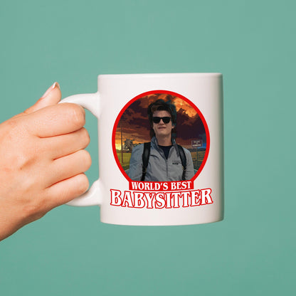 Mug with a person holding a baby and 'World's Best Babysitter' text on a green background
