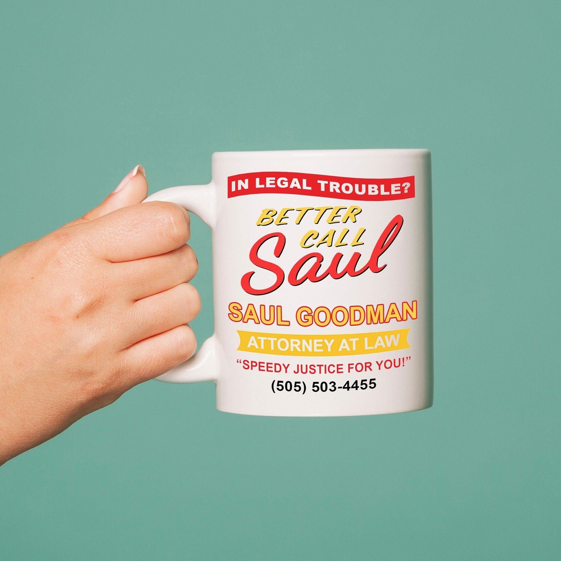 Hand holding a mug with 'Better Call Saul' text against a teal background