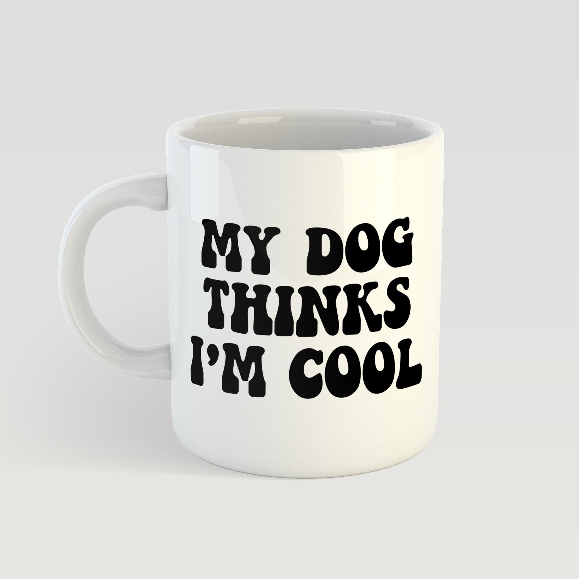 White mug with black text 'My dog thinks I'm cool' on a light gray background
