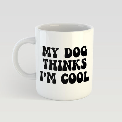 White mug with black text 'My dog thinks I'm cool' on a light gray background