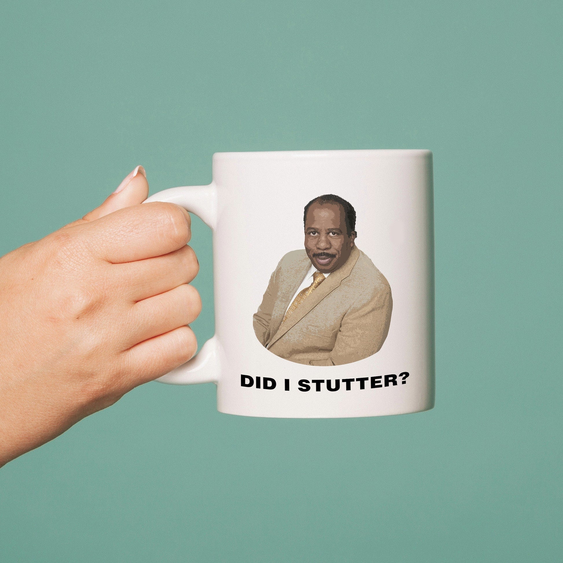 Mug with a printed image and text 'Did I Stutter?' held by a hand against a teal background