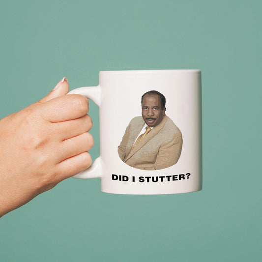 Mug with a printed image and text 'Did I Stutter?' held by a hand against a teal background