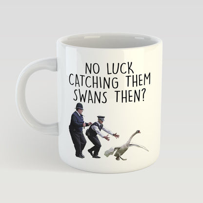 Mug with a humorous design of two police officers chasing a swan, accompanied by the text 'No luck catching them swans then?'.