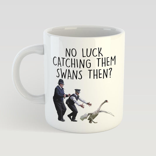 Mug with a humorous design of two police officers chasing a swan, accompanied by the text 'No luck catching them swans then?'.