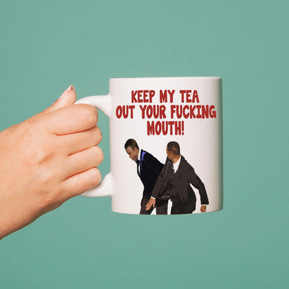A white mug with a sublimation printed graphic featuring an image of two people and the text 'KEEP MY F*CKING tea out your mouth!'.